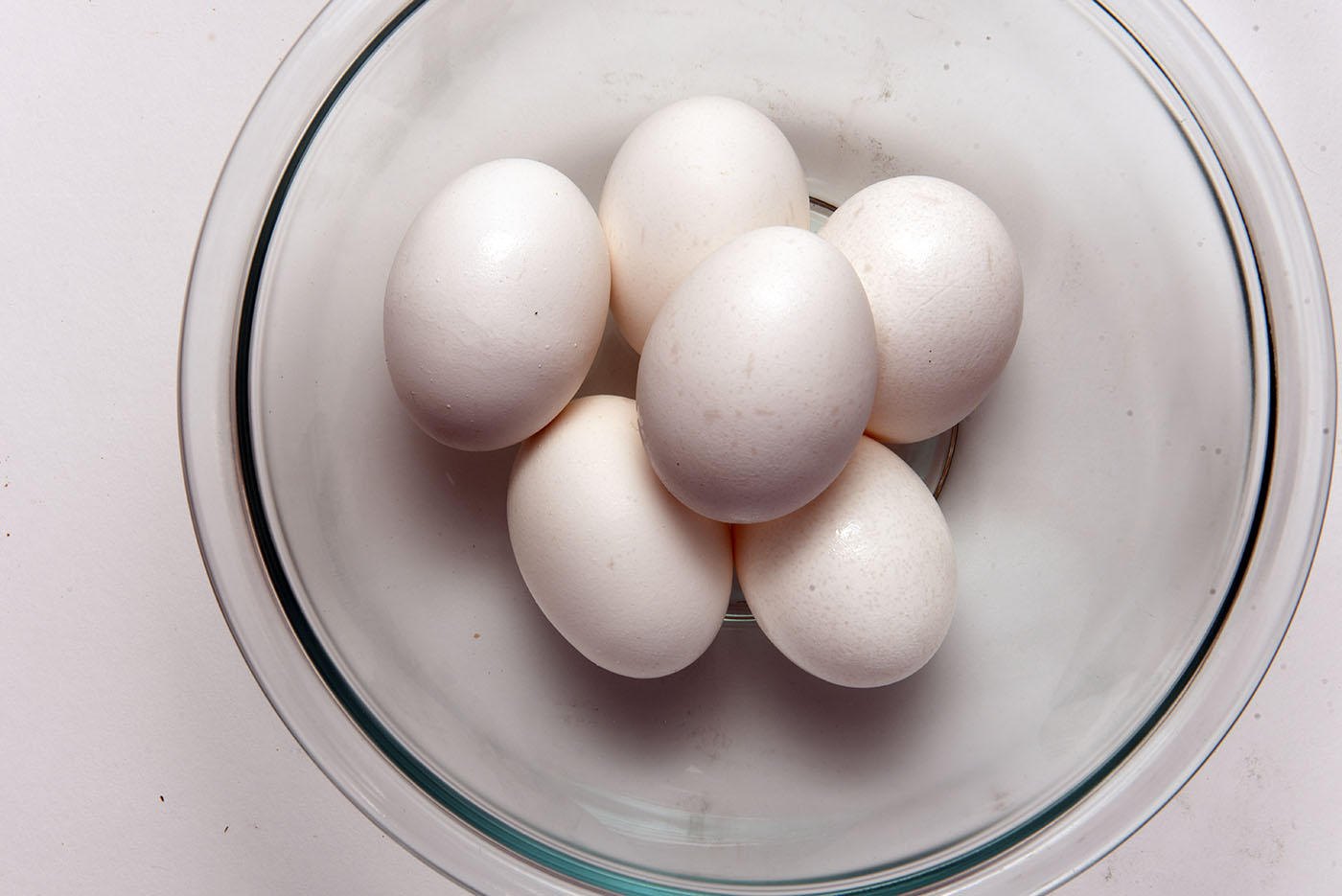 A clear glass bowl holding six boiled eggs.