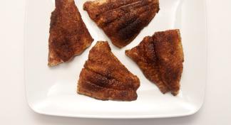 Four pieces of oven blackened catfish on a square, white serving platter.