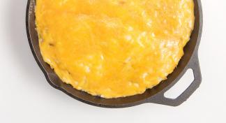 An iron skillet filled with Shepherd's Pie; a recipe using ground beef, green beans, mashed potatoes, and cheese.